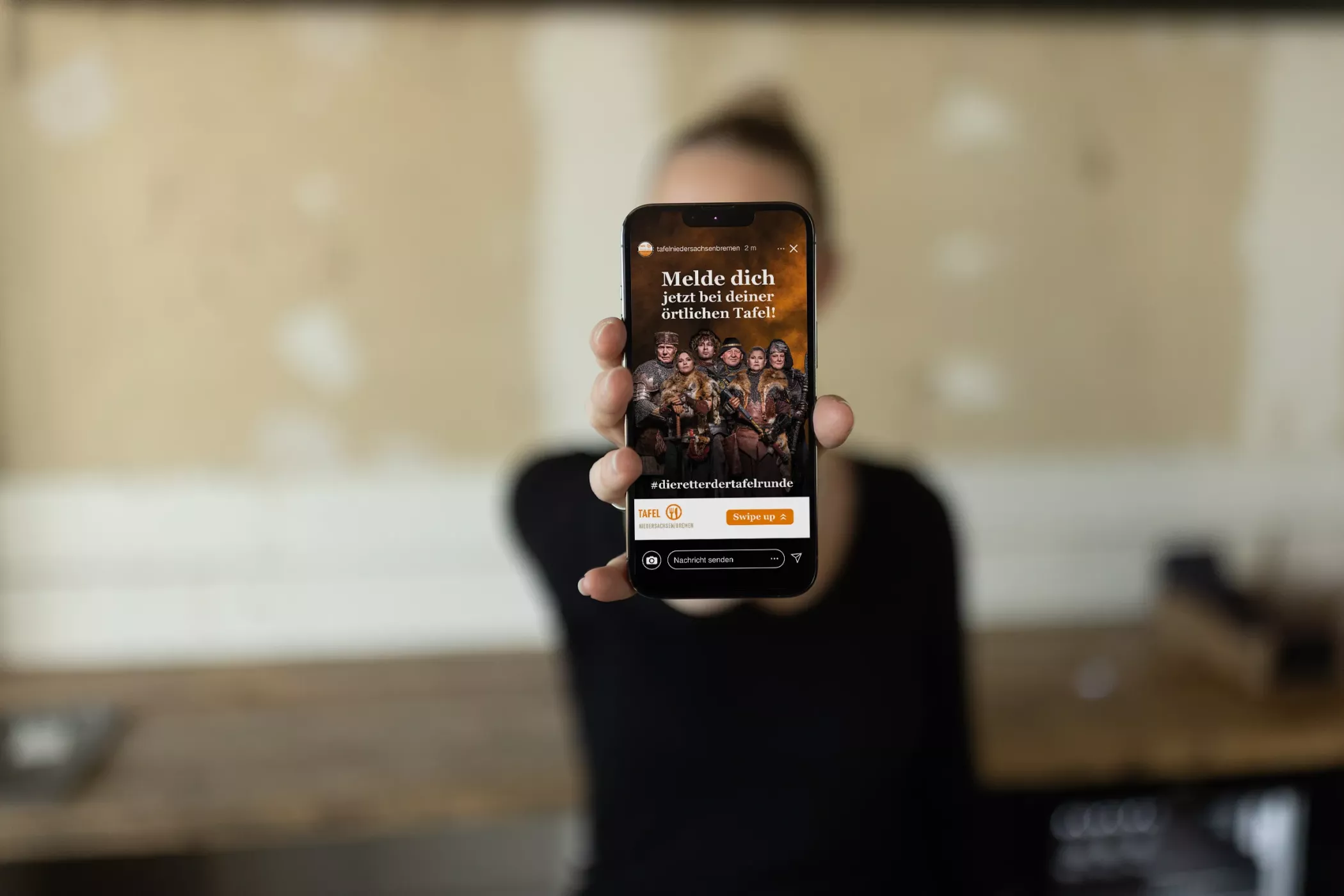Eine Frau hält ein Handy mit dem Plakatmotiv der