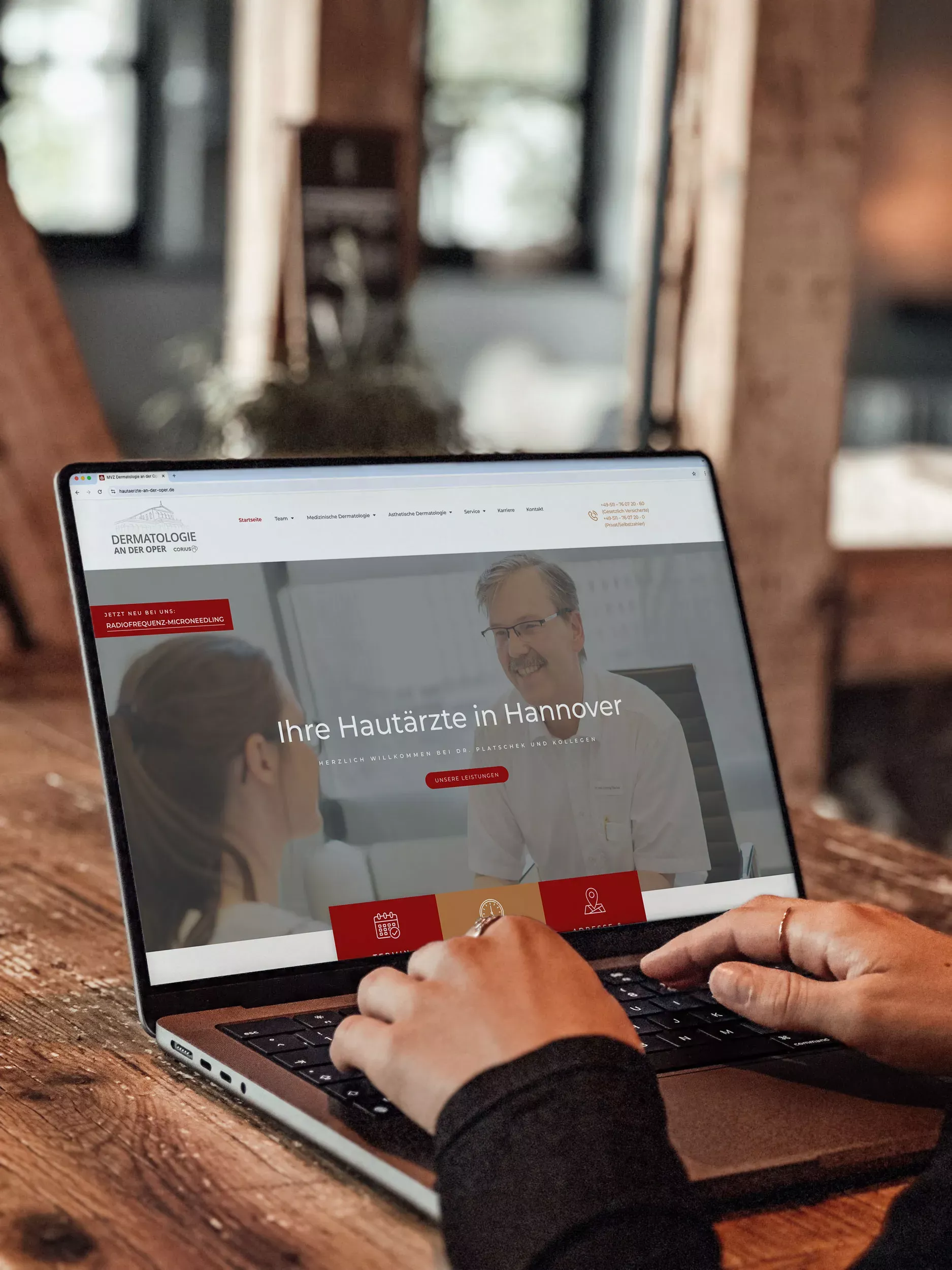 Eine Person tippt auf einem Laptop, auf dessen Bildschirm die Website der 