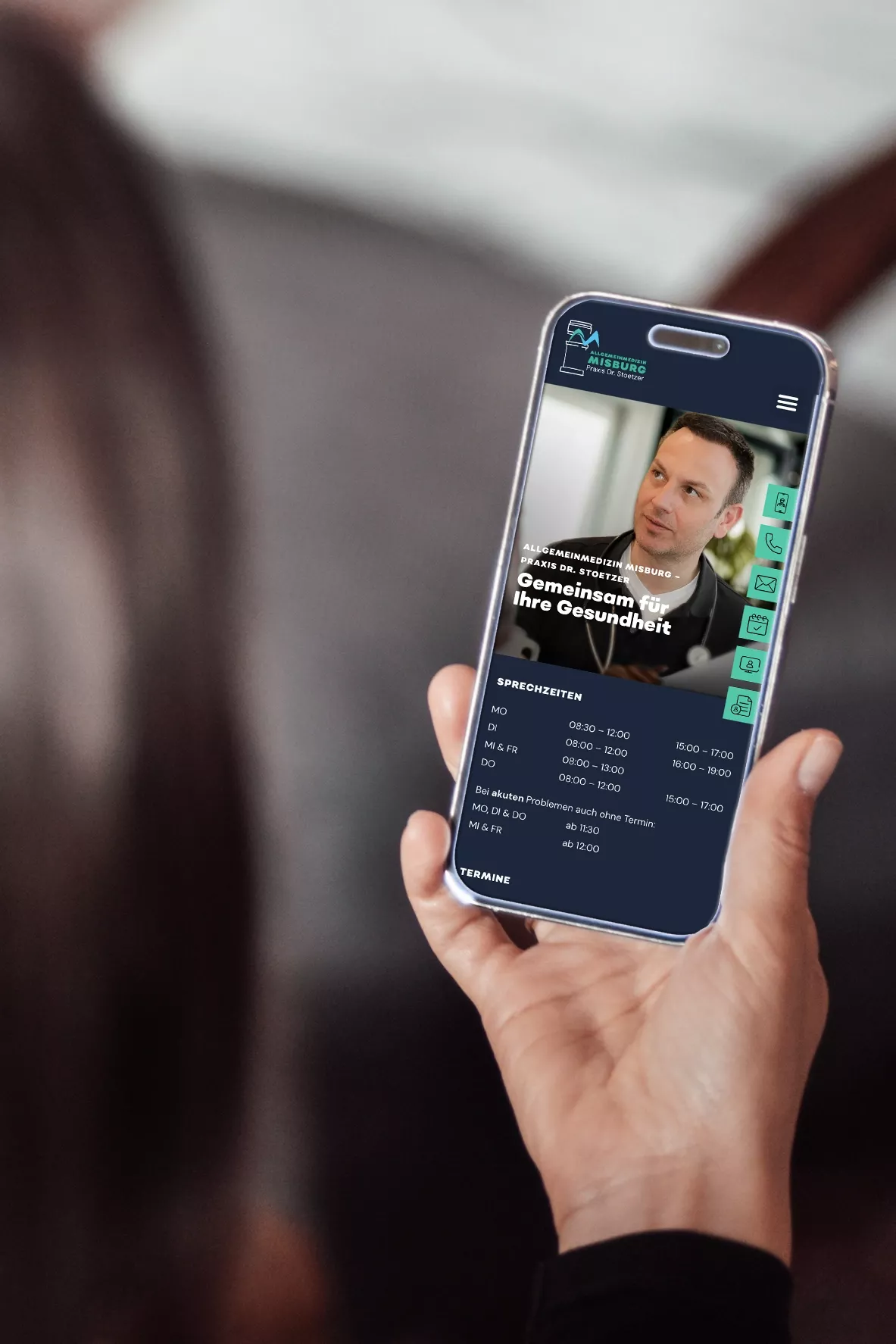 Eine Hand hält ein Smartphone, auf dessen Bildschirm die mobile Version der Website der 