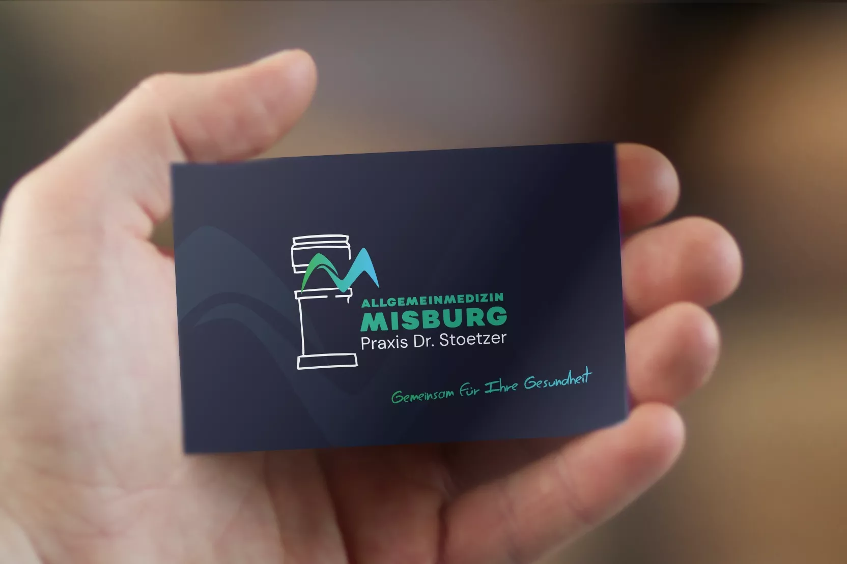 Eine Hand hält eine dunkelblaue Visitenkarte der 