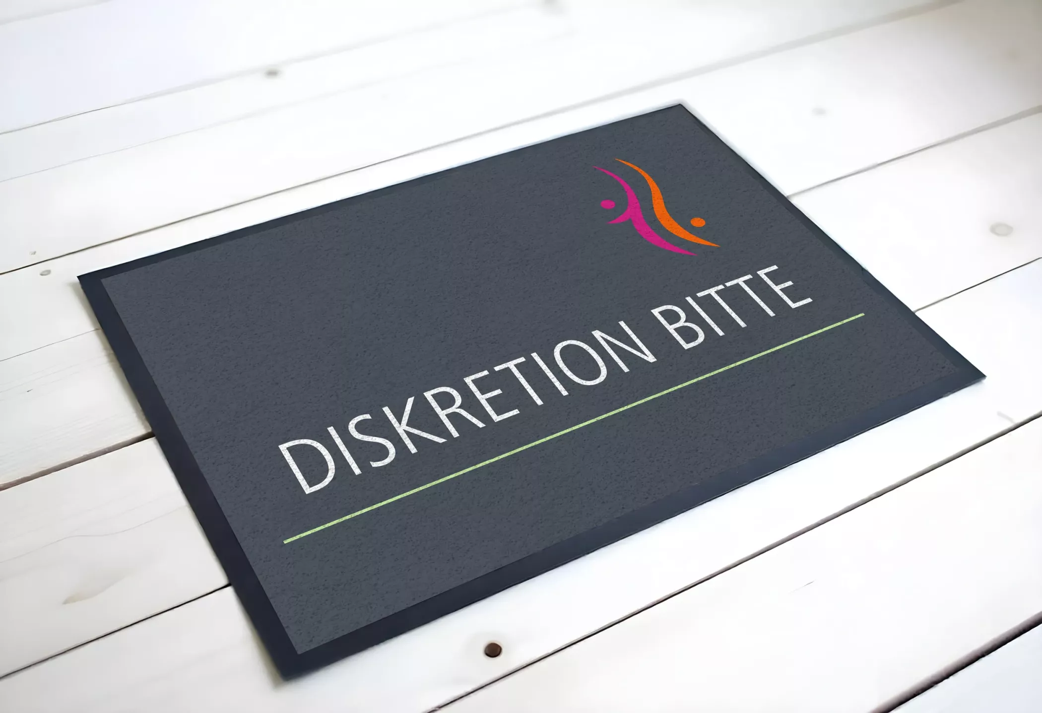 Dunkle Fußmatte mit der Aufschrift „Diskretion bitte“ und dem farbigen Logo der Frauenarztpraxis Dr. Altevogt und Rühmkorb-Claassen. Die Matte liegt auf hellem Holzboden und verbindet diskrete Hinweisgebung mit dem modernen Corporate Design der Praxis.