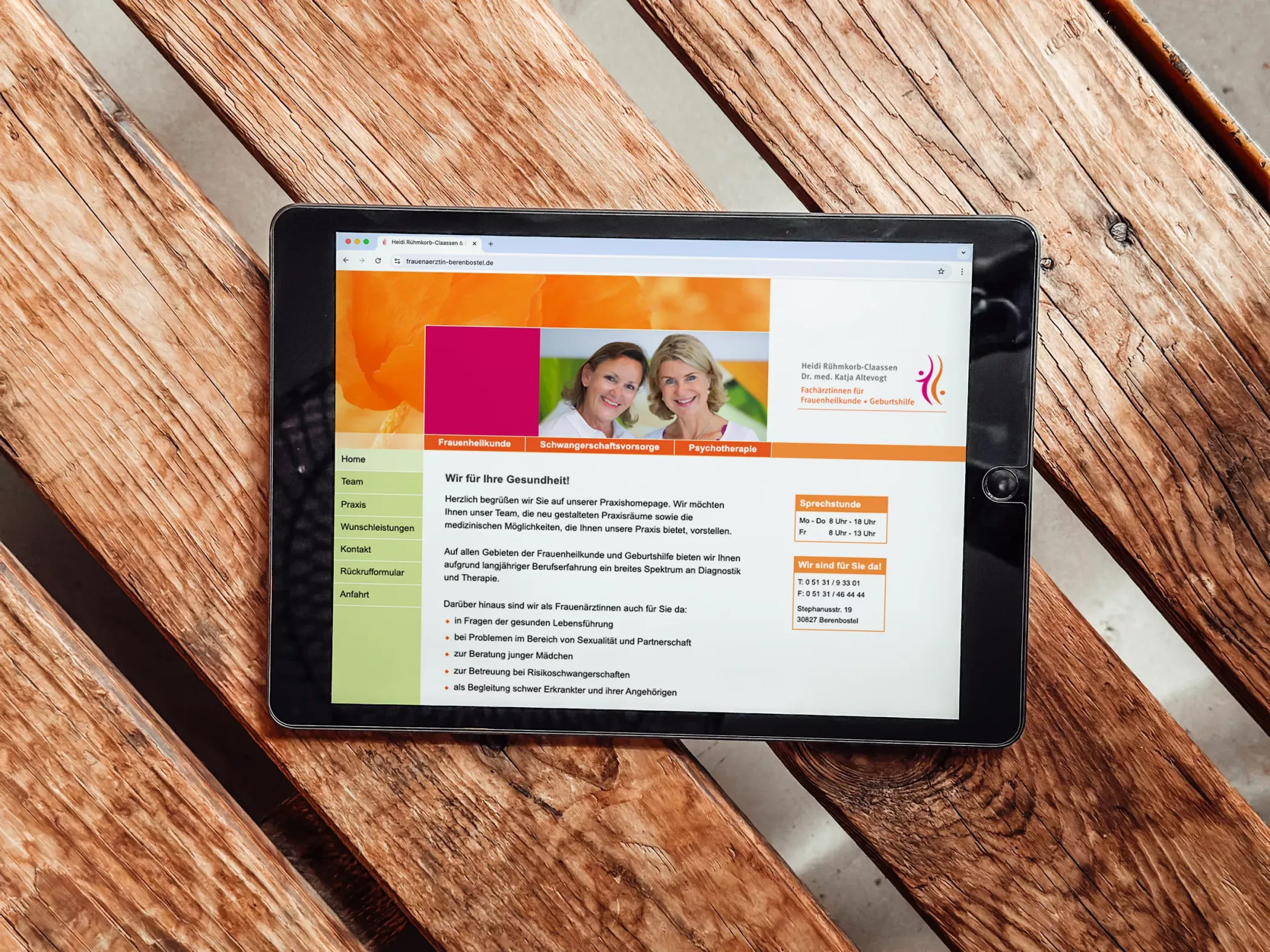 Tablet auf einer Holzbank zeigt die Website der Frauenarztpraxis Dr. Altevogt und Rühmkorb-Claassen. Auf dem Bildschirm sind ein Bild der beiden Ärztinnen, die Hauptmenüpunkte sowie ein Begrüßungstext zur Praxis zu sehen. Das Webdesign ist freundlich, übersichtlich und farblich auf das Corporate Design abgestimmt.