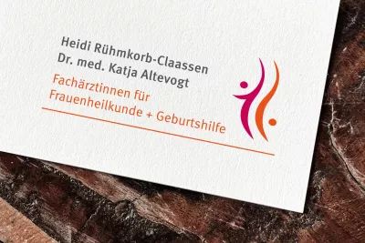 Nahaufnahme eines Druckdokuments der Frauenarztpraxis Heidi Rühmkorb-Claassen und Dr. med. Katja Altevogt. Zu sehen sind die Namen der Ärztinnen, die Berufsbezeichnung „Fachärztinnen für Frauenheilkunde + Geburtshilfe“ in oranger Schrift sowie ein stilisiertes Logo mit zwei abstrakten Figuren in Magenta und Orange auf weißem Hintergrund. Das Design wirkt modern, freundlich und vertrauensvoll.