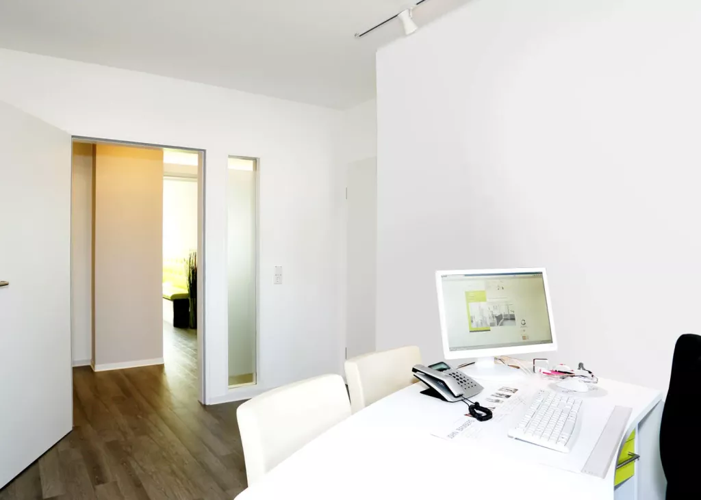 Ein Tisch mit einem Monitor steht in einem Behandlungsraum.