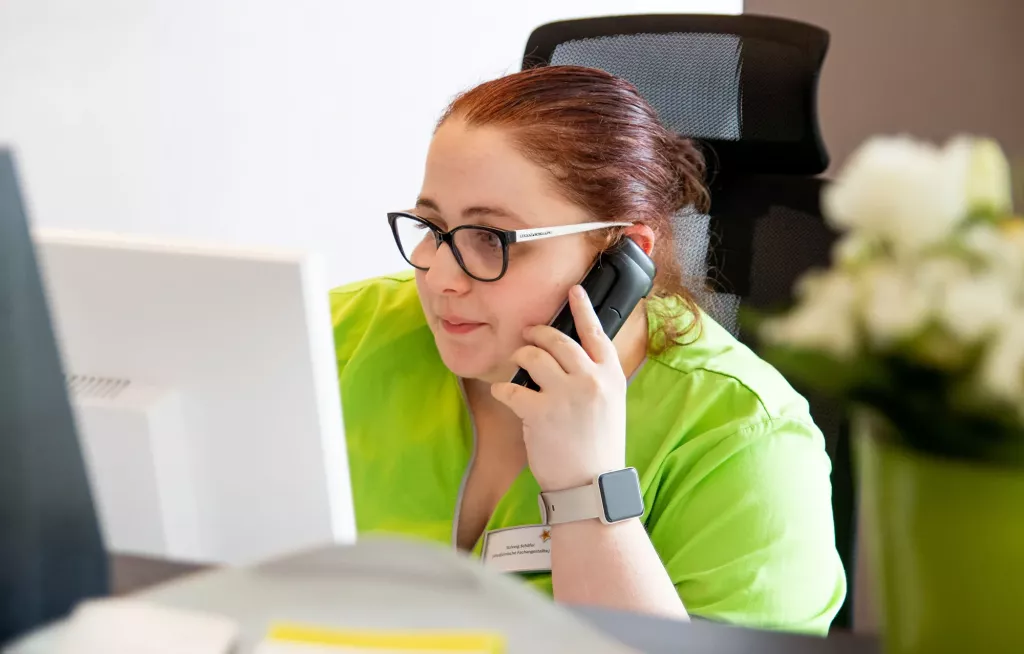 Eine Arzthelferin telefoniert mit Patientinnen.