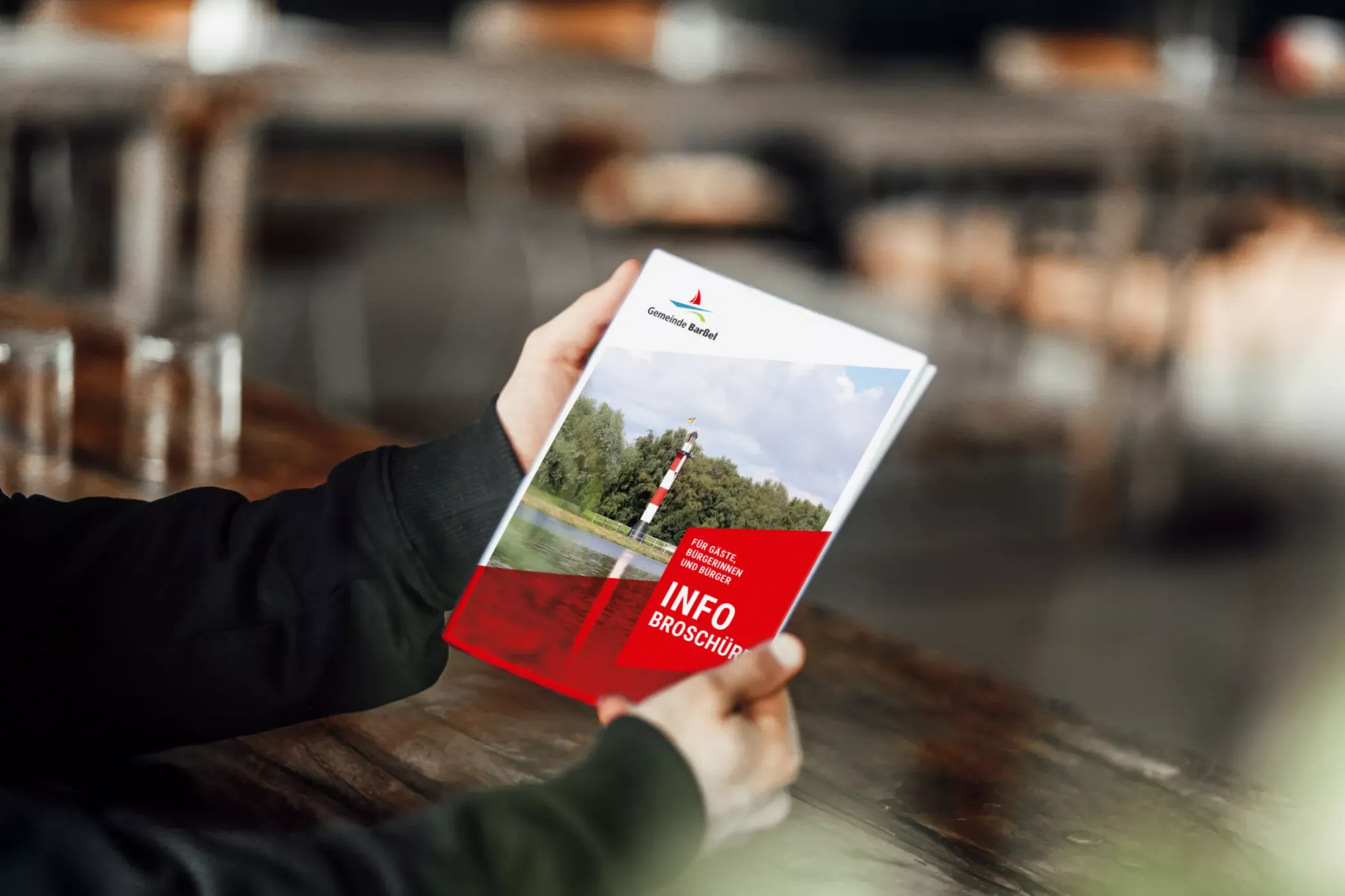 Person hält eine Informationsbroschüre der Gemeinde Barßel in den Händen, die zentrale Informationen und Angebote der Gemeinde übersichtlich darstellt.