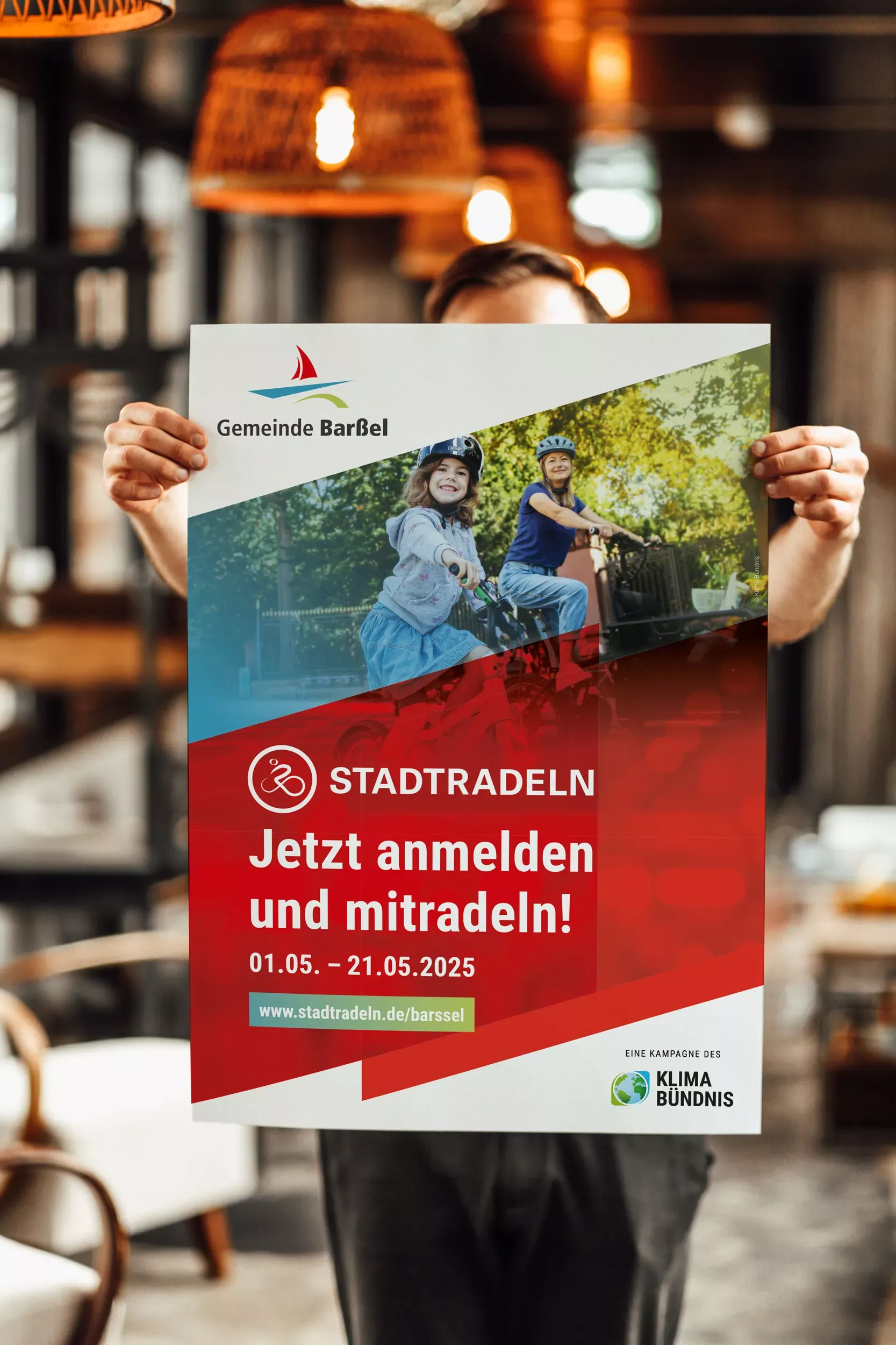 Person hält ein Plakat der Gemeinde Barßel zur Stadtradeln-Aktion mit dem Aufruf „Jetzt anmelden und mitradeln“ sowie Informationen zum Aktionszeitraum.