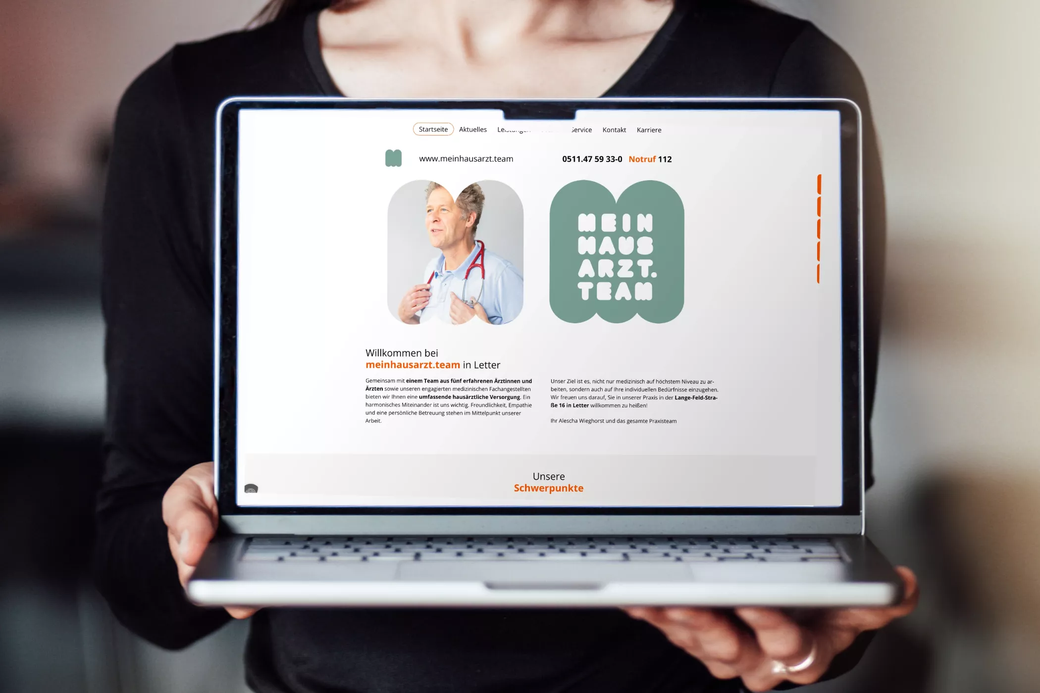 Eine Person hält einen Laptop, auf dessen Bildschirm die Startseite der Website von meinhausarzt.team zu sehen ist. Links ein Begrüßungstext mit dem Bild einer Ärztin im weißen Kittel, rechts das grüne Logo „MEINHAUSARZT.TEAM“ in verspielter Typografie. Die Website wirkt freundlich, modern und übersichtlich.