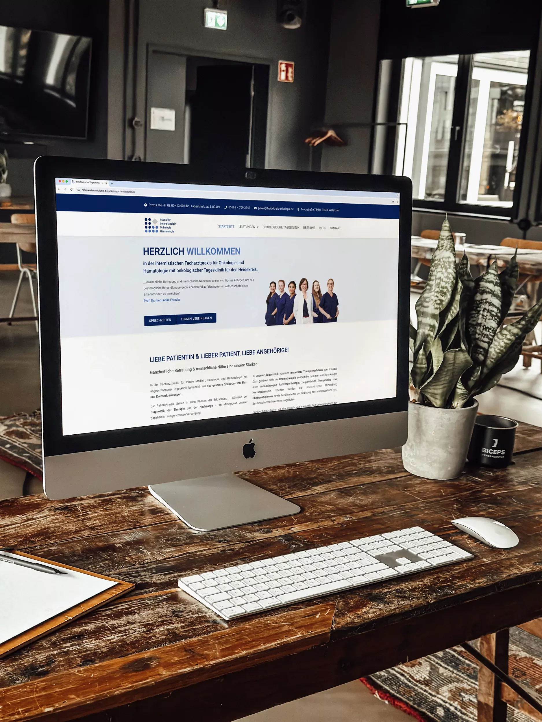 Ein iMac auf einem Holztisch zeigt die Website der 