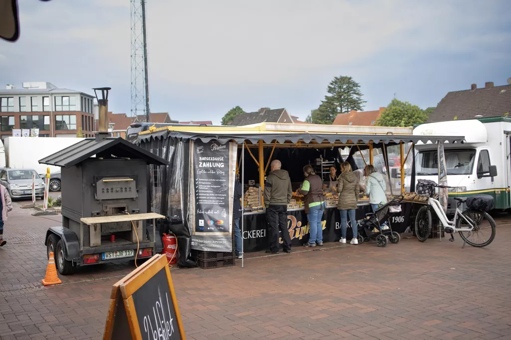 Kunden kaufen Brot an einem Marktstand.