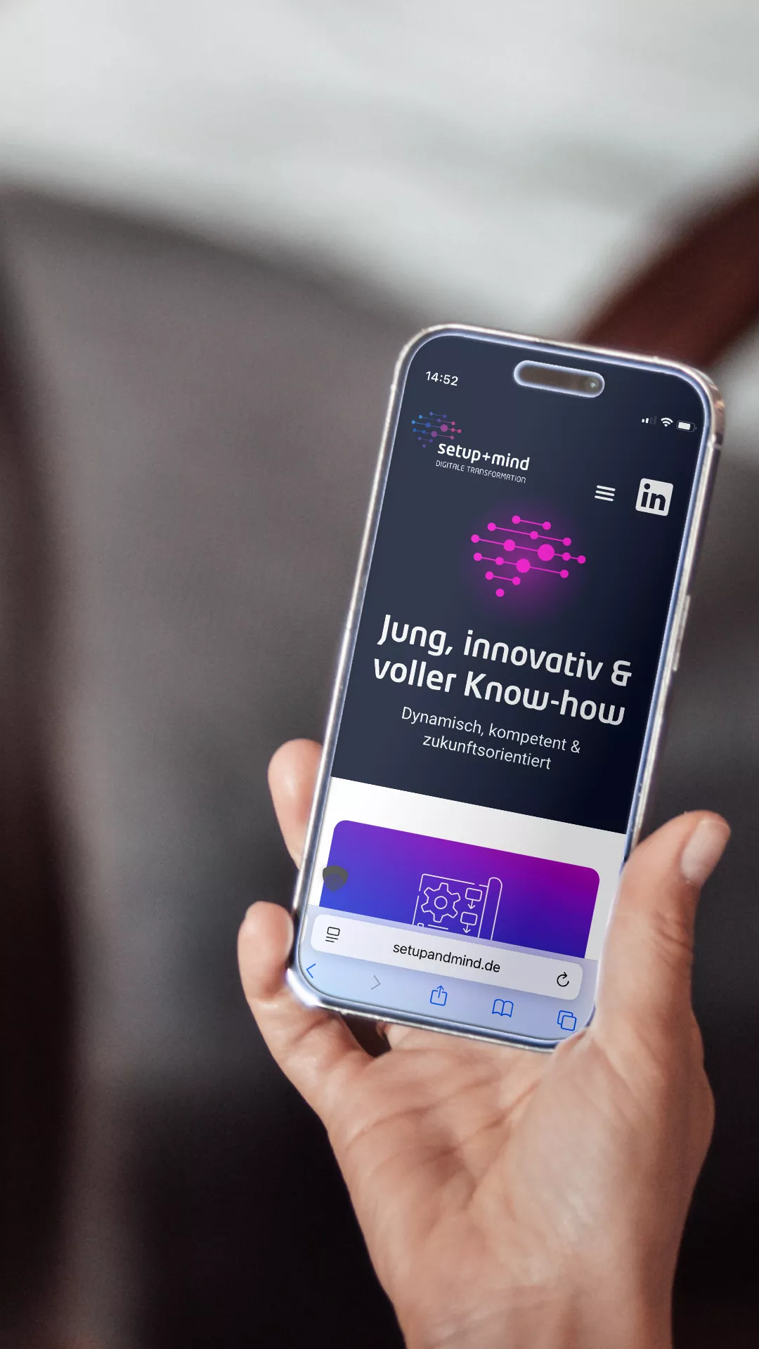 Person hält ein Smartphone, auf dem die mobil optimierte Website von setup+mind mit dem Claim „Jung, innovativ & voller Know-how“ angezeigt wird.