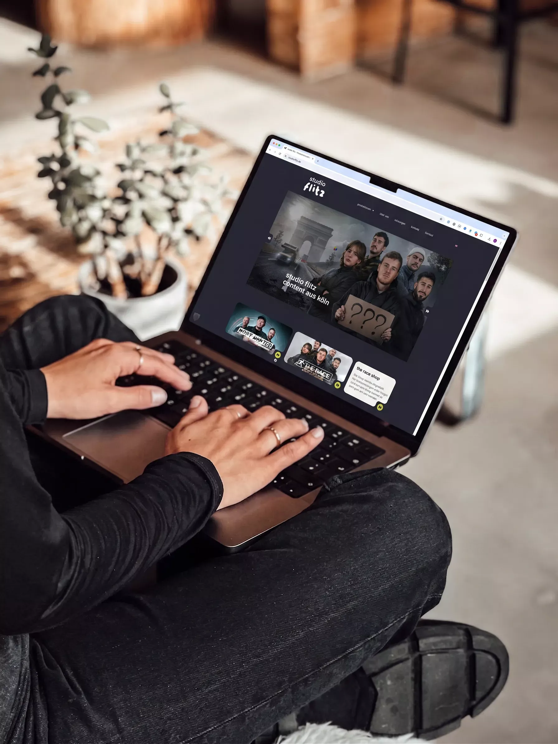 Eine Person sitzt auf dem Boden und arbeitet an einem MacBook, auf dem die neue Website von studio flitz zu sehen ist, die die Werbeagentur BICEPS als Webdesign-Projekt umgesetzt hat.