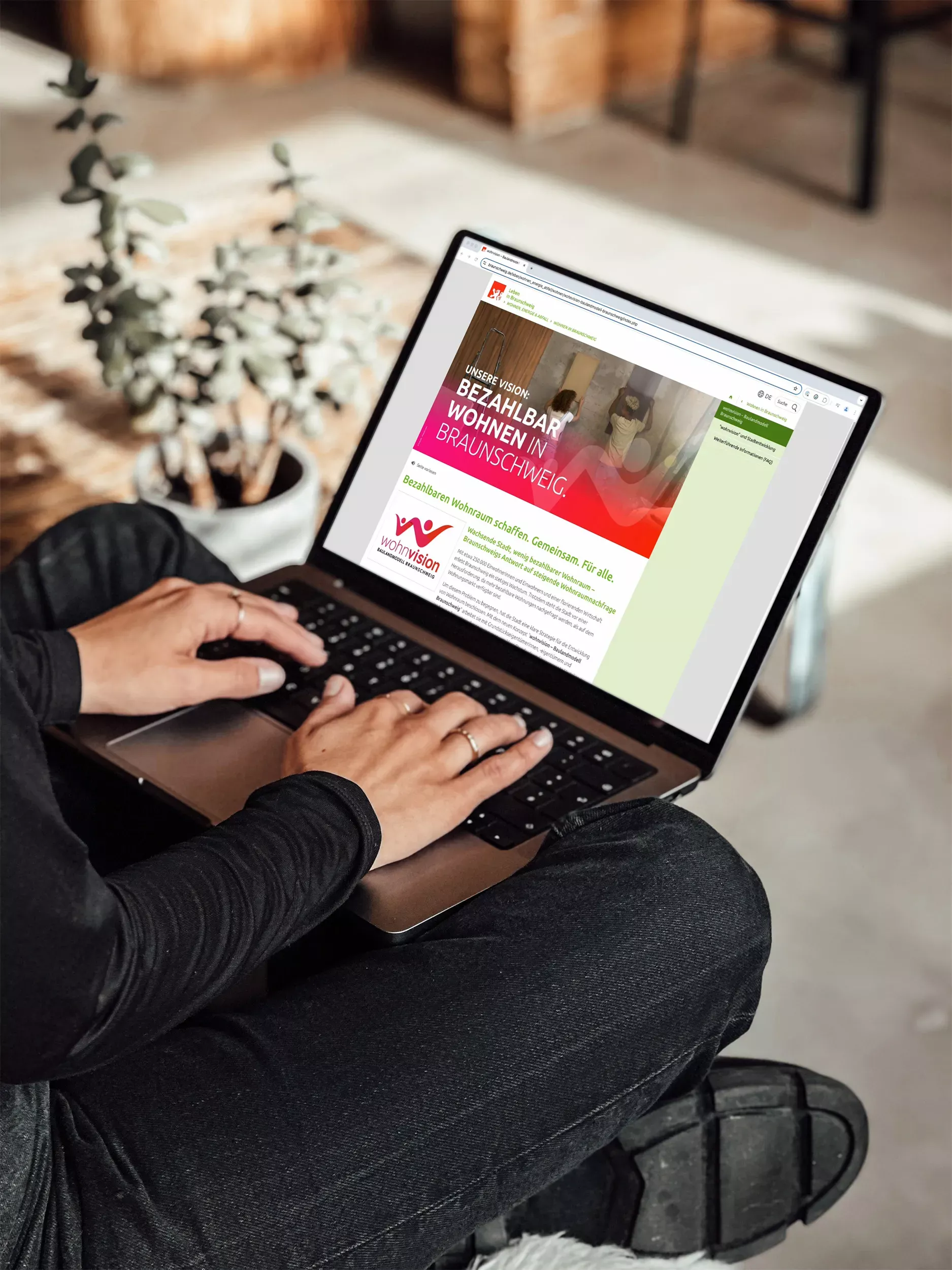 Person mit Laptop auf dem Schoß besucht die Website der Wohnvision Braunschweig. Auf dem Bildschirm ist der Einstieg mit dem Video sowie weiterführende Informationen zum Baulandmodell zu sehen.